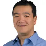 Portrait of a smiling man in a blue collared shirt.