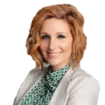 Professional woman with red hair smiling, wearing a light blazer and patterned blouse.