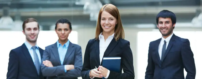 Two professional women in business attire smiling confidently.