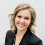 Smiling young woman with blonde hair in professional attire.