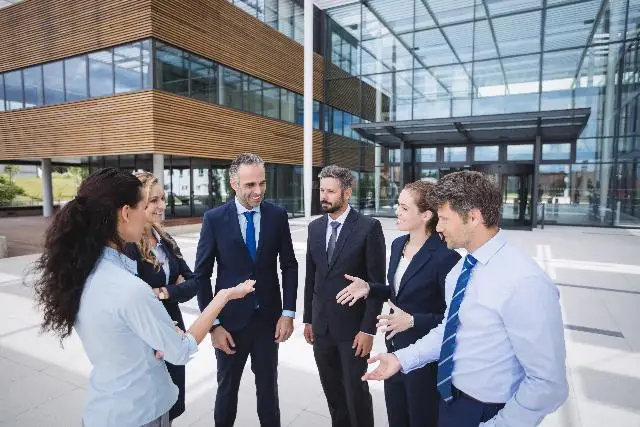 Business professionals shaking hands outside a modern office building.