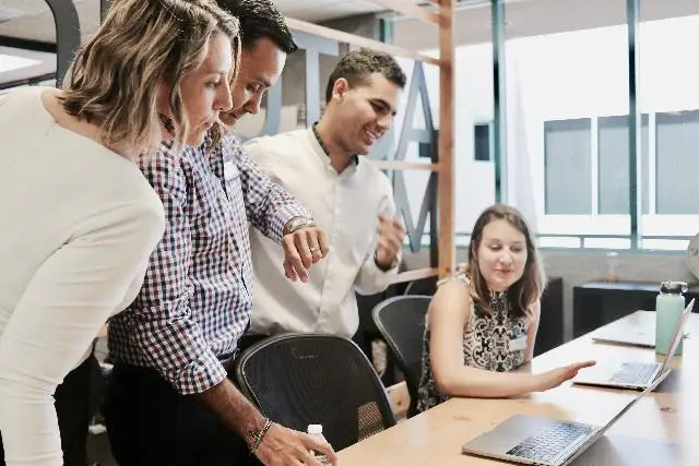 Colleagues engaged in a lively discussion around a laptop.