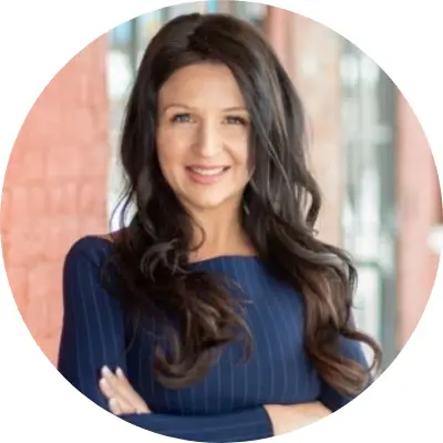 Confident woman with long dark hair and a blue top smiling.