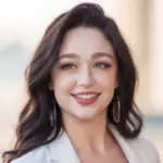 A smiling woman with long dark hair and hoop earrings.