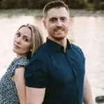 Couple posing outdoors with a scenic water background.