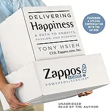 Book titled 'Delivering Happiness' by Tony Hsieh with a Zappos box.