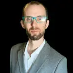 Professional man in glasses and gray suit against black background.