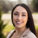 Portrait of a smiling woman outdoors in business attire.