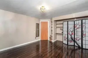 Empty room with polished wooden floors and built-in shelves.