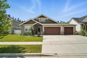 Modern single-story house with a three-car garage and manicured front lawn.
