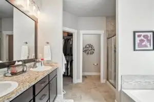 Modern bathroom with dual sinks, a walk-in closet, and elegant decor.