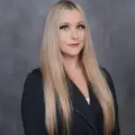 Professional portrait of a woman with long blonde hair in a black blazer.