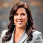 Professional woman with dark hair smiling in a gray blazer.
