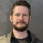 Man with beard and short hair smiling.