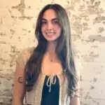 Smiling woman with tattoos against brick wall