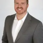 A person standing wearing a gray suit